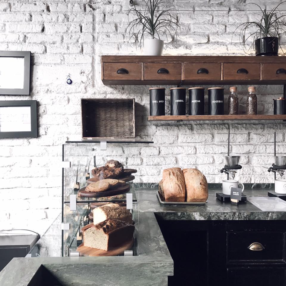 The best places to co-work in Mexico City | A view of the pastry counter at Dosis, with banana bread and loaves on two shelves behind a glass case, and in front of a white-painted brick wall