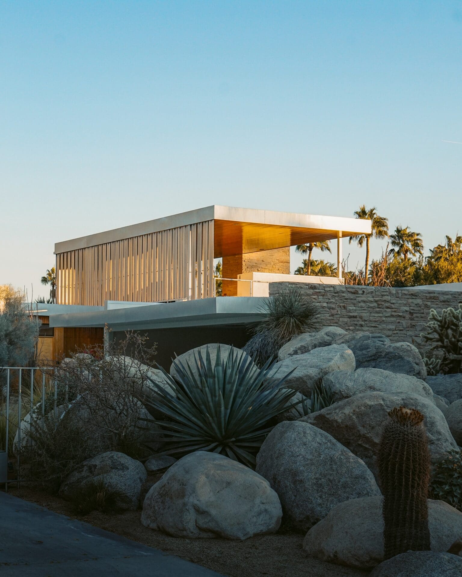 What to do in Palm Springs, California | A midcentury modern home lit in the golden evening sun against a cloudless blue sky