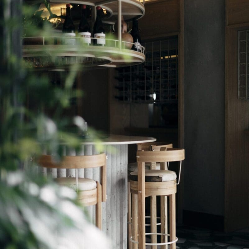 The best restaurants in Mexico City | A view of the bar at Malix, with a high wooden stool facing a curved counter, and a black-and-white checked floor