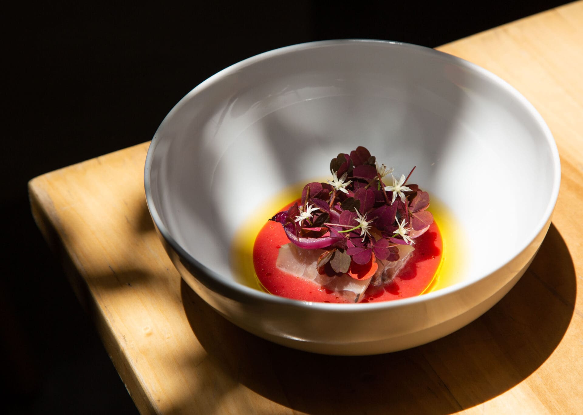 The best restaurants in Mexico City | A pale grey bowl with a delicate dish topped by purple flowers at Migrante