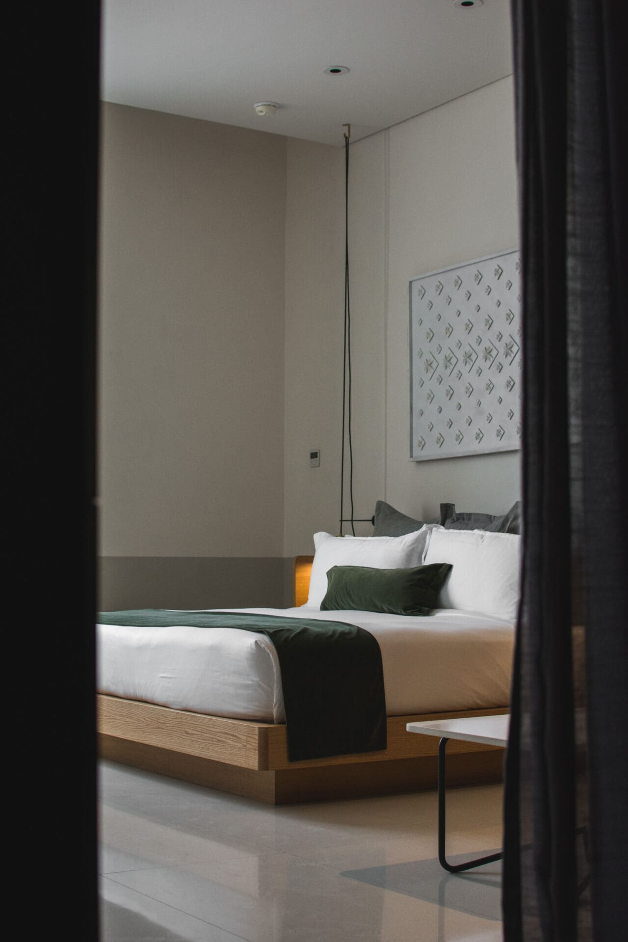 The best hotels in Mexico City | A view of a bedroom in Umbral. The bed is viewed between two long dark drapes.