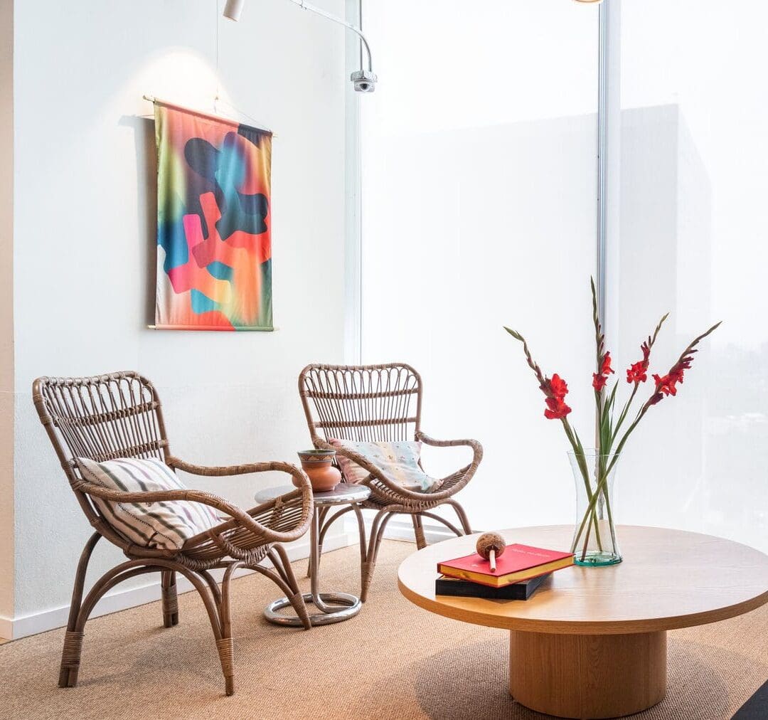 The best co-working spaces in Mexico City | wicker furniture in front of a white wall with a colourful painting at WeWork in Insurgentes Sur