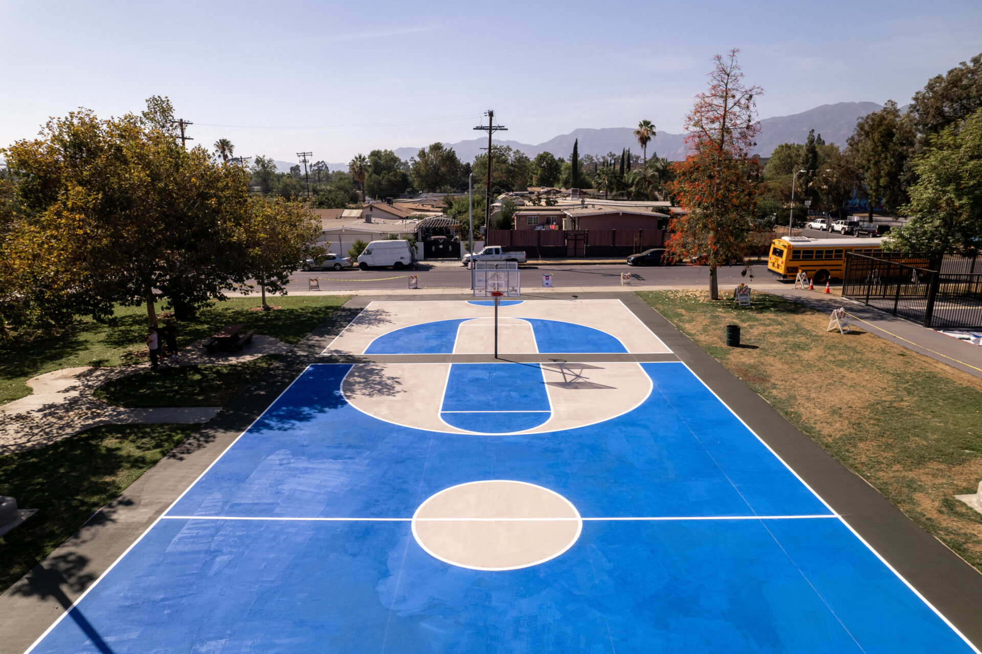 An aerial view of the blue and white painted mural on a basketball court in Pacoima, Los Angeles. The mural uses reflective paint that reduces surface temperatures.