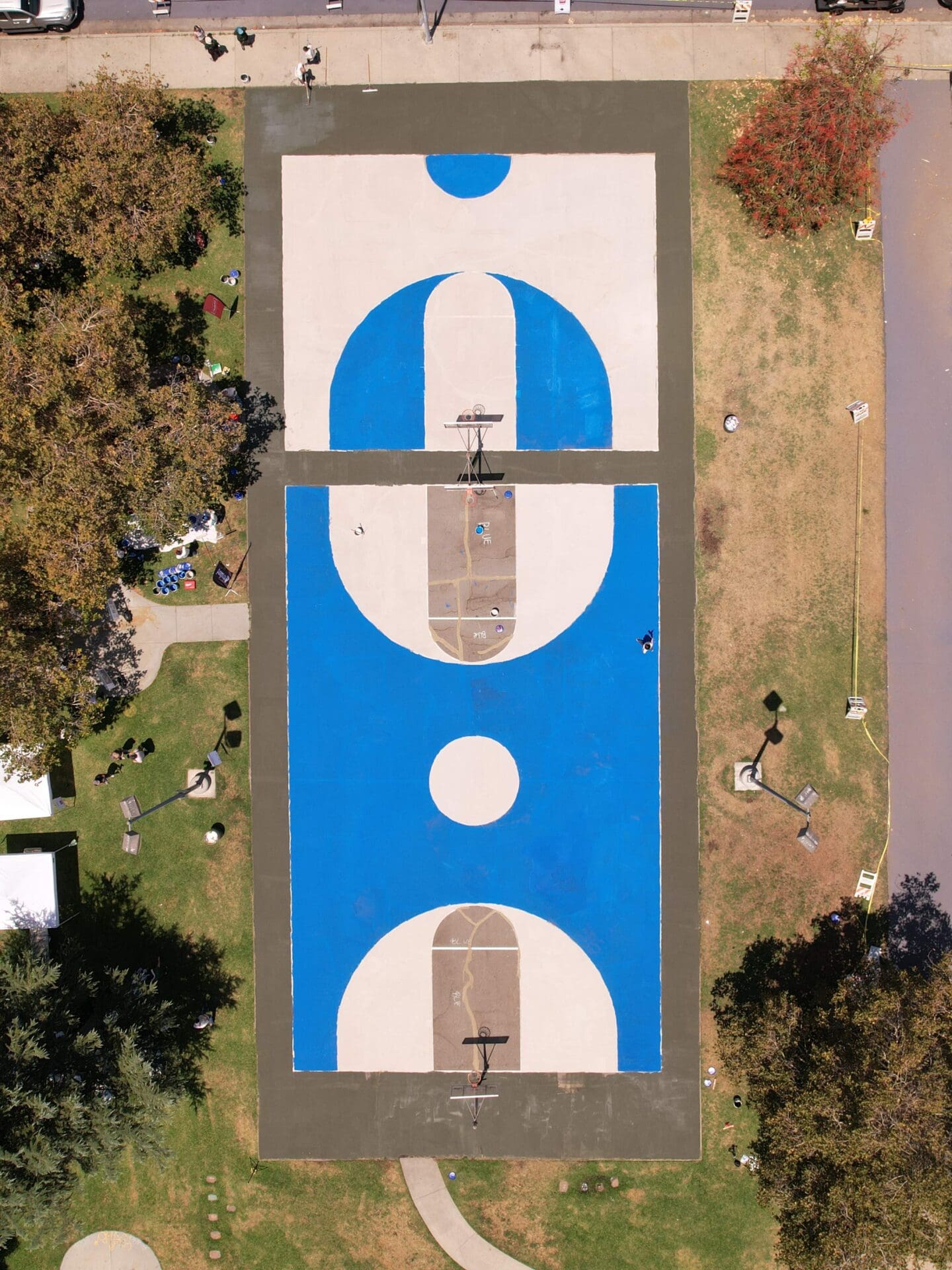 The LA neighbourhood using reflective paint to tackle rising temperatures | An aerial view of a basketball court in Pacoima, Los Angeles, with views of the blue and white mural painted on its surface with reflective paint