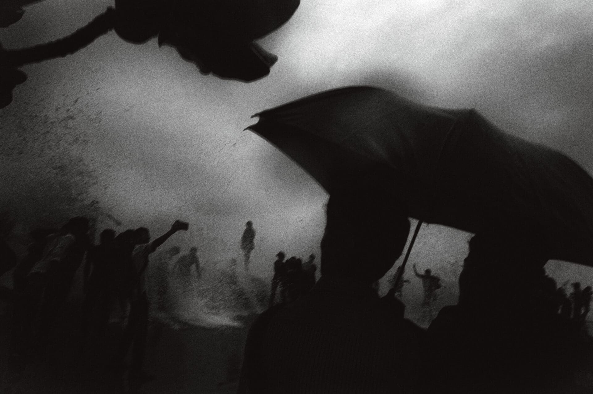 Photographer Sunhil Sippy on Mumbai | a more close-up view of a person holding an umbrella against a stormy sky