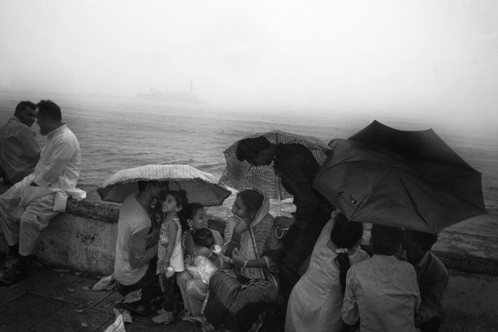 Photographer Sunhil Sippy on Mumbai | people holding umbrellas cluster by the sea wall