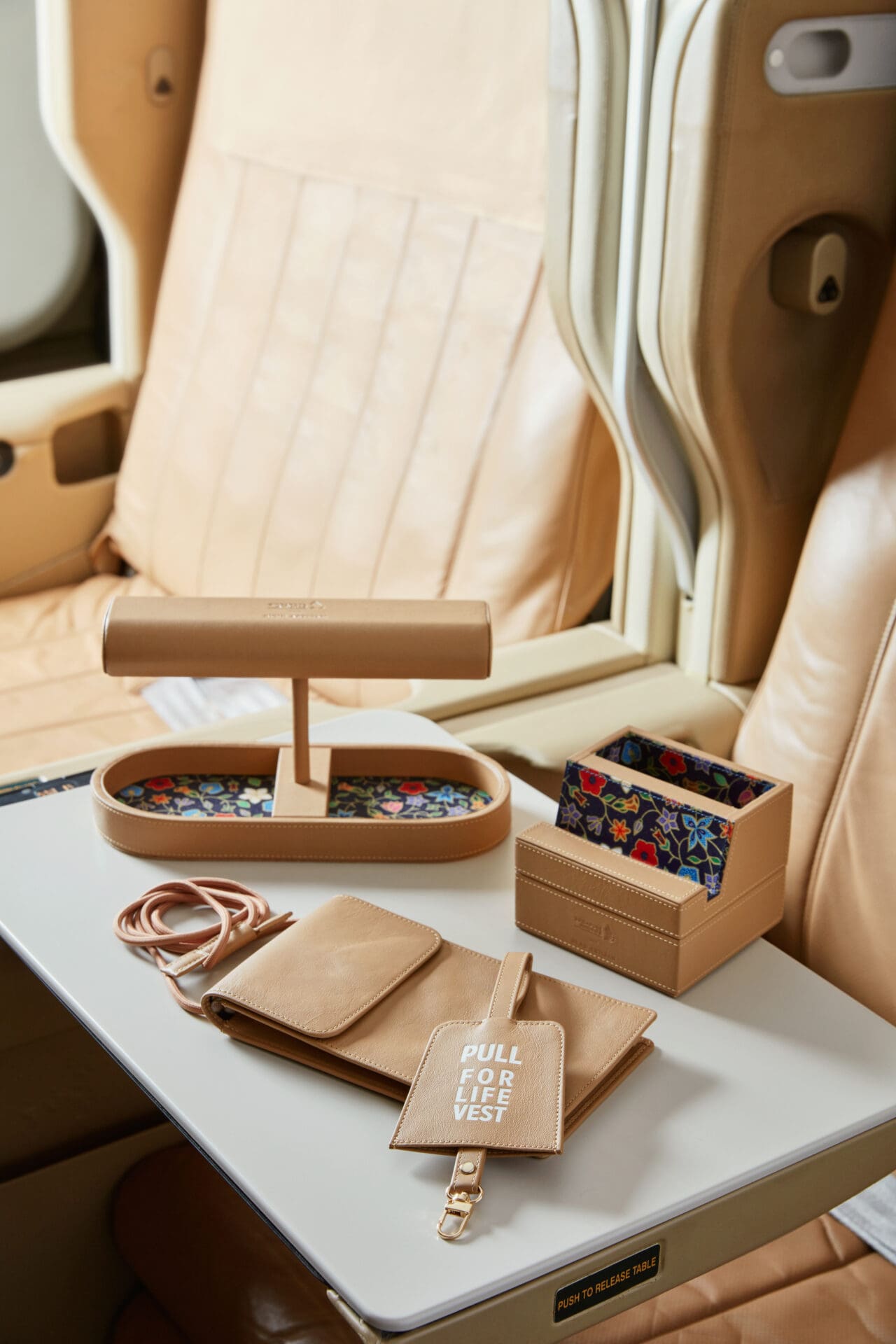 Airline news and trends | A collection of camel-coloured leather good sits on an airplane seat table
