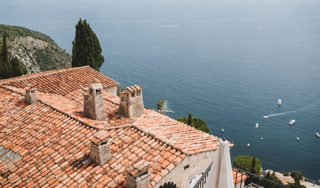 Running in Nice | A view over the terracotta-tiled roof of one of Éze's medieval buildings, looking out to sea