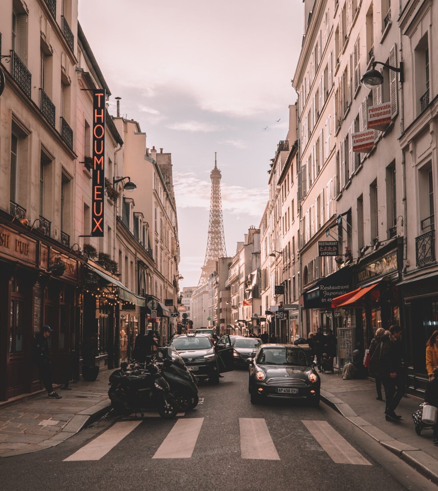 Cultural tours for the modern era | The eiffel tower is visible behind the facade of a Parisian street