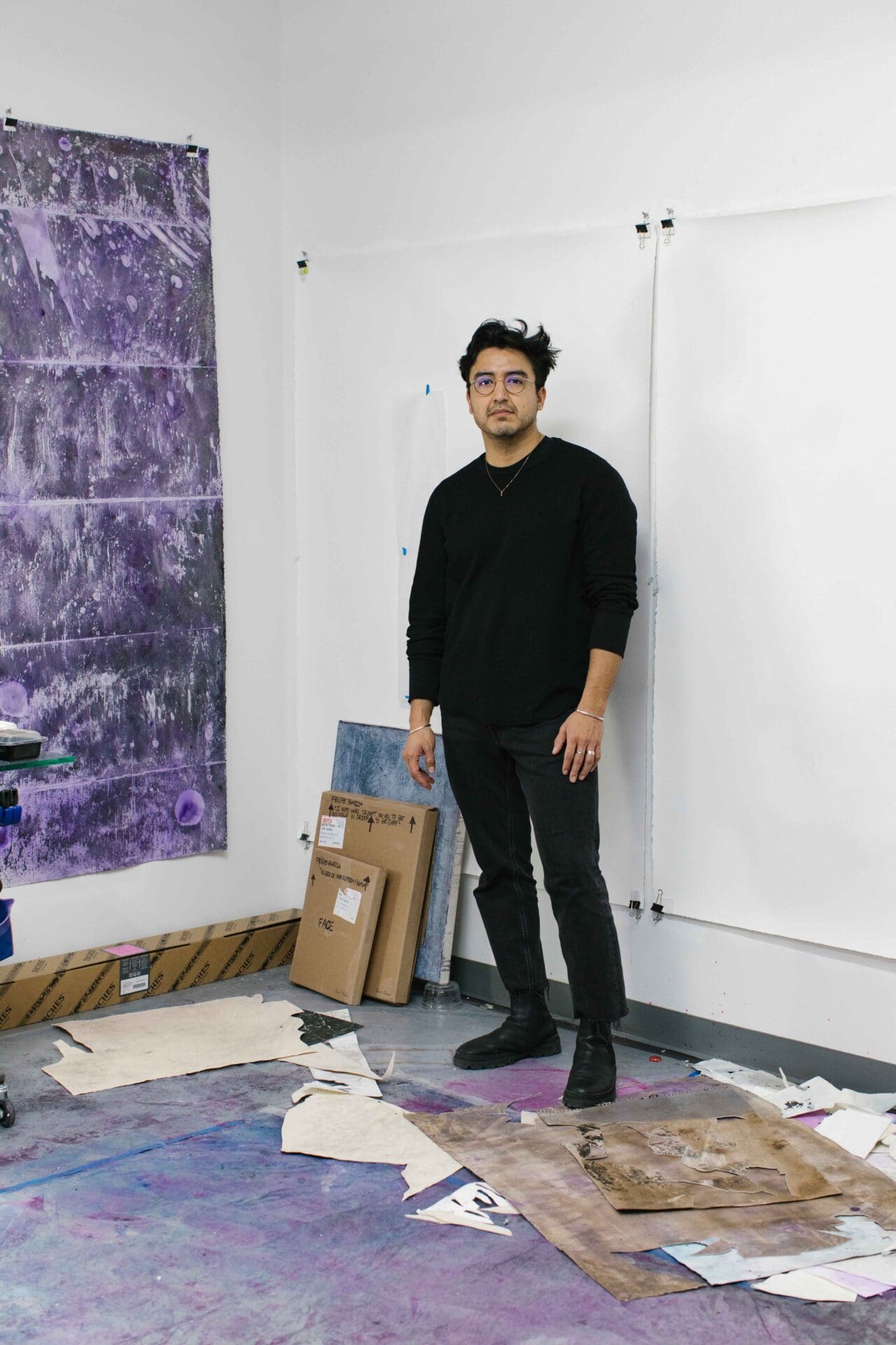 Felipe Baeza | Felipe Baeza standing in his studio, with a work hanging on the wall beside him