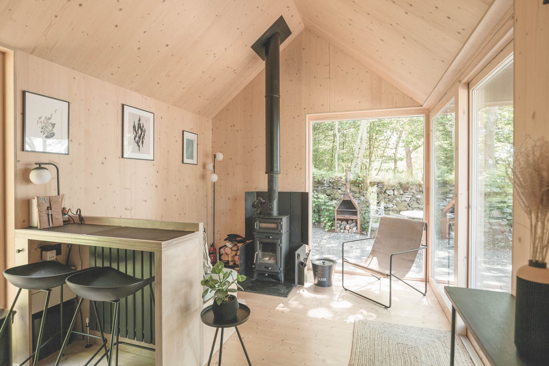 Kip Hideaways: inside a cabin, with a wood burner in an open-plan living space with armchairs and a breakfast bar