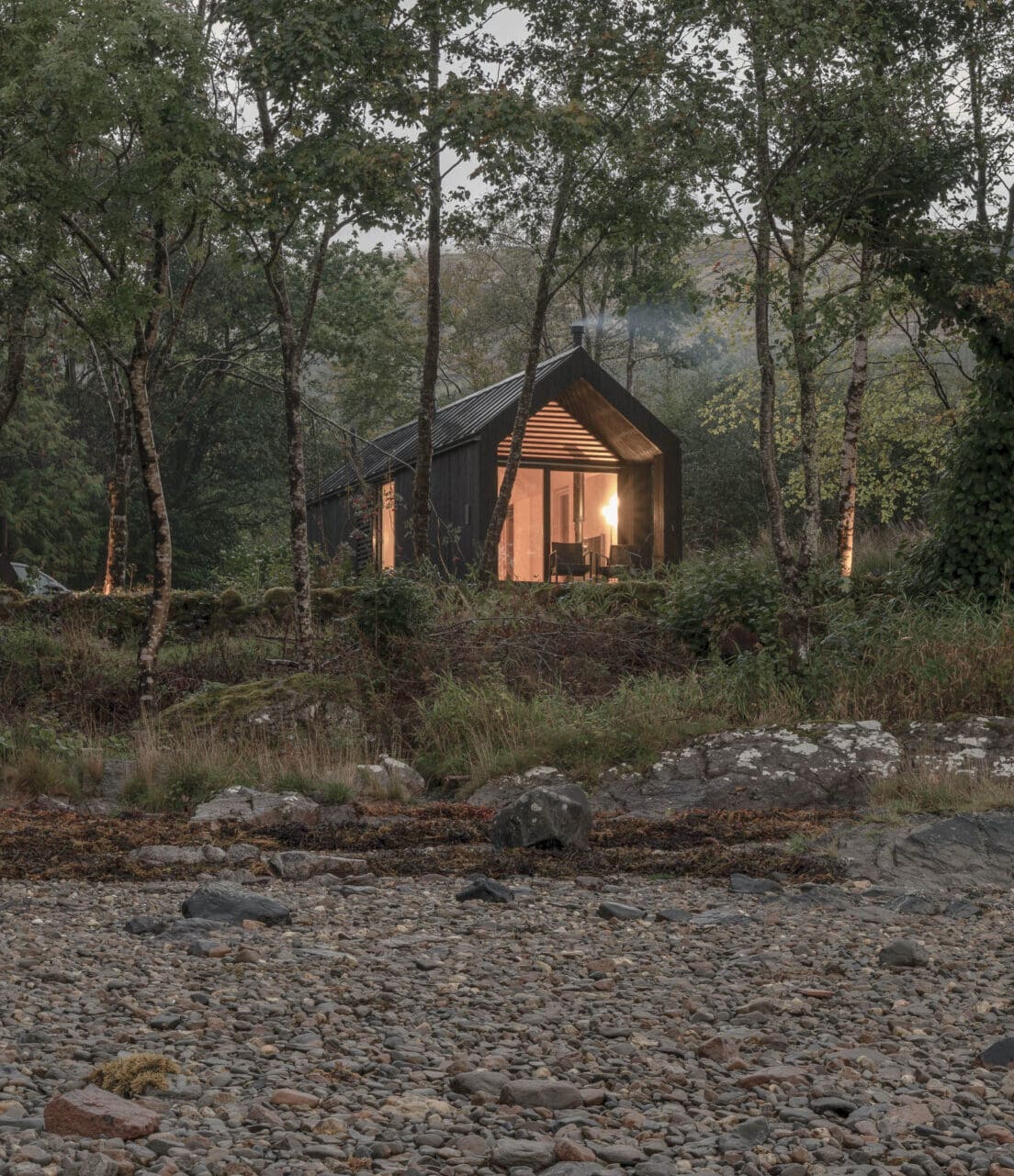 Holidays rentals are adapting for digital nomads | Kip Hideaways Loch Fyne retreats: a corrugated iron cabin with floor-to-ceiling windows is lit from within in a remote forest