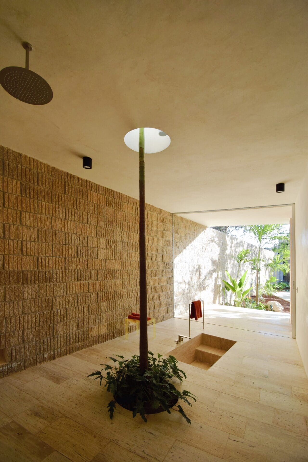 A large tiled room with a wood burner and steps descending into a bath