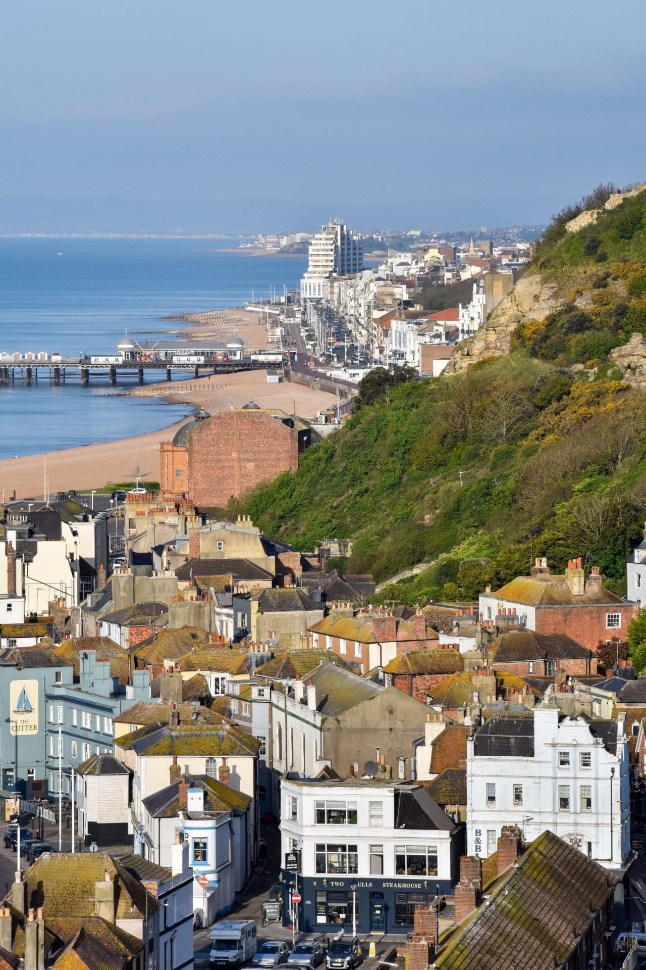 A weekend in Hastings | A view over the rooftops and hillside of Hastings, with the pier and beach to the left
