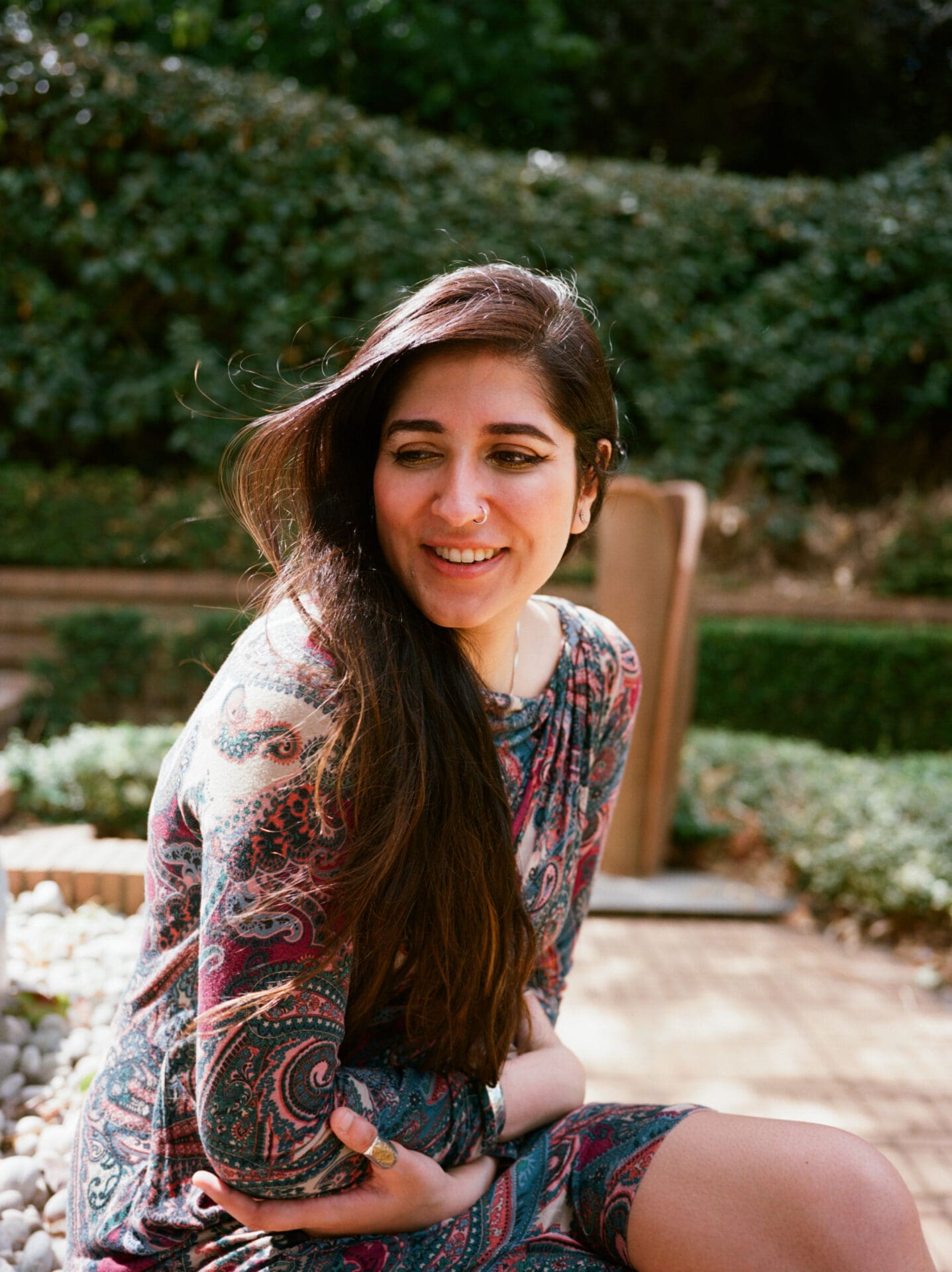 An interview with poet Nikita Gill | Nikita Gill sits outside with her arms folded.