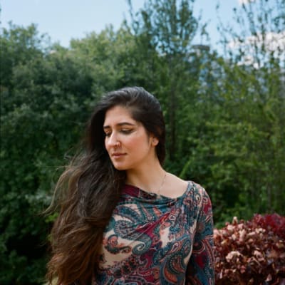 An interview with poet Nikita Gill | A portrait of poet Nikita Gill, wearing a paisley patterned dress, and sat outside