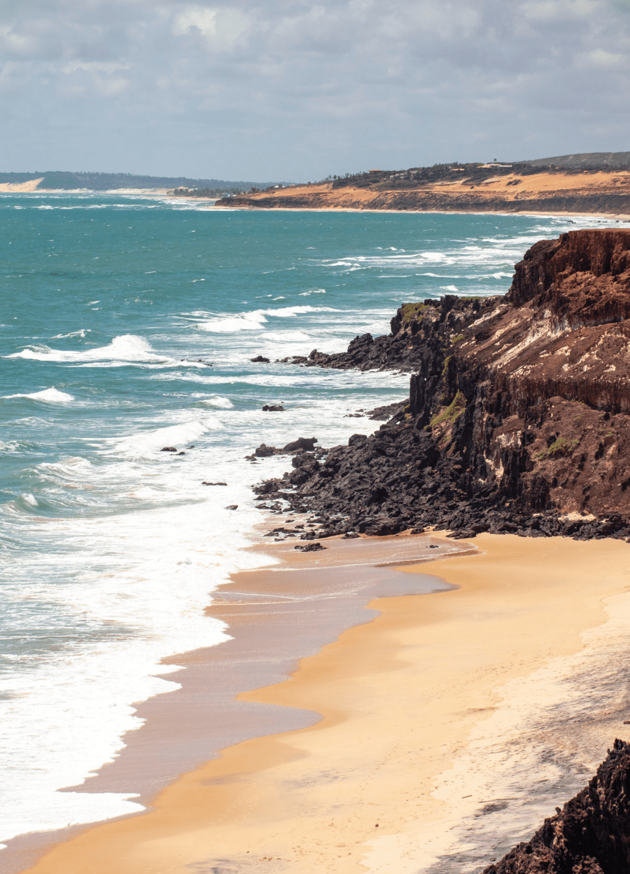 NomadX Pipa, Brazil | A golden-sand beach, with white-foamed waves and a cliff backdrop