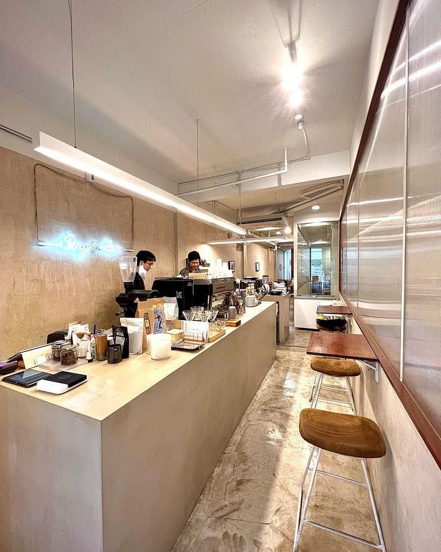 Best Bangkok coffee shops | A long, narrow room with a white counter and floor, the counter topped by coffee-making paraphenalia