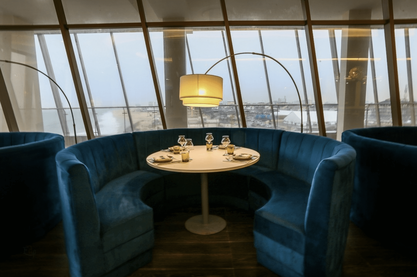 Cosy blue banquet seating surrounding a circular table by a window at 788 on the Sea, Lagos