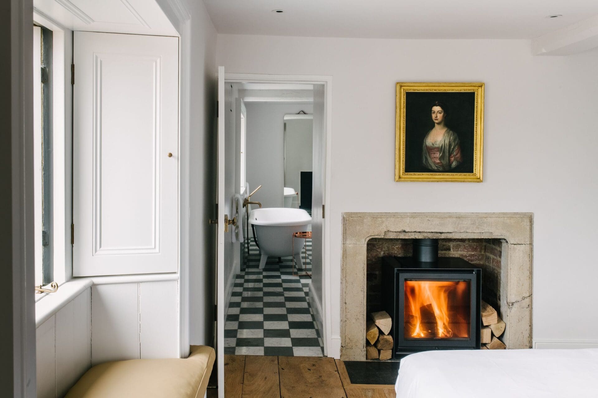 Interiors at The Newt, Somerset | a roaring fireplace beside a door leading to a checkerboard tiled floor