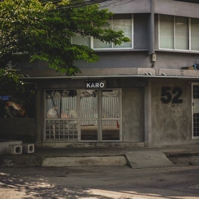 The best coffee shops in Bangkok | Karo coffee shop occupies a stark concrete building, with its entrance on a diagonal corner wall with a big green tree to the left-hand side