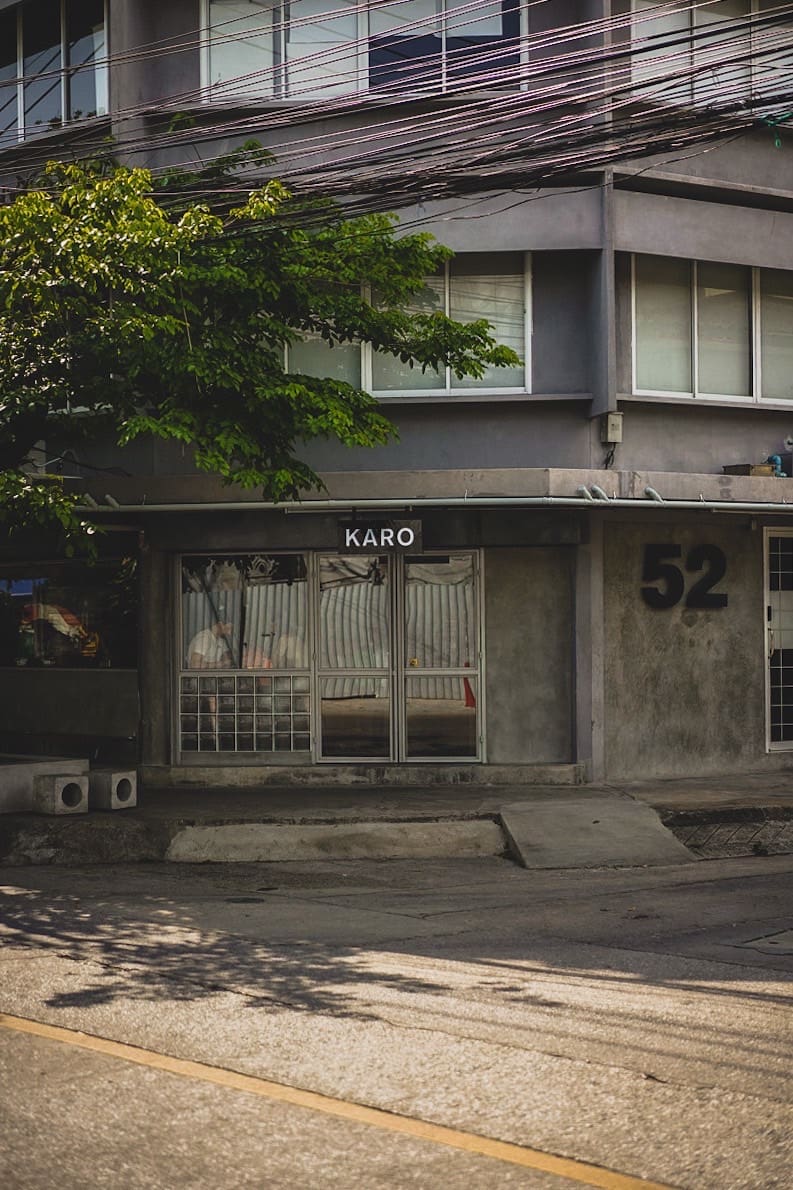 The best coffee shops in Bangkok | Karo coffee shop occupies a stark concrete building, with its entrance on a diagonal corner wall with a big green tree to the left-hand side