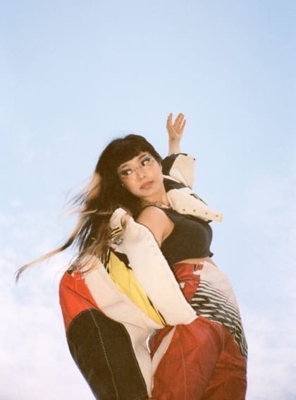 An interview with Thai pop singer Pyra | Pyra stood against the blue sky with her left arm outstretched to the sky