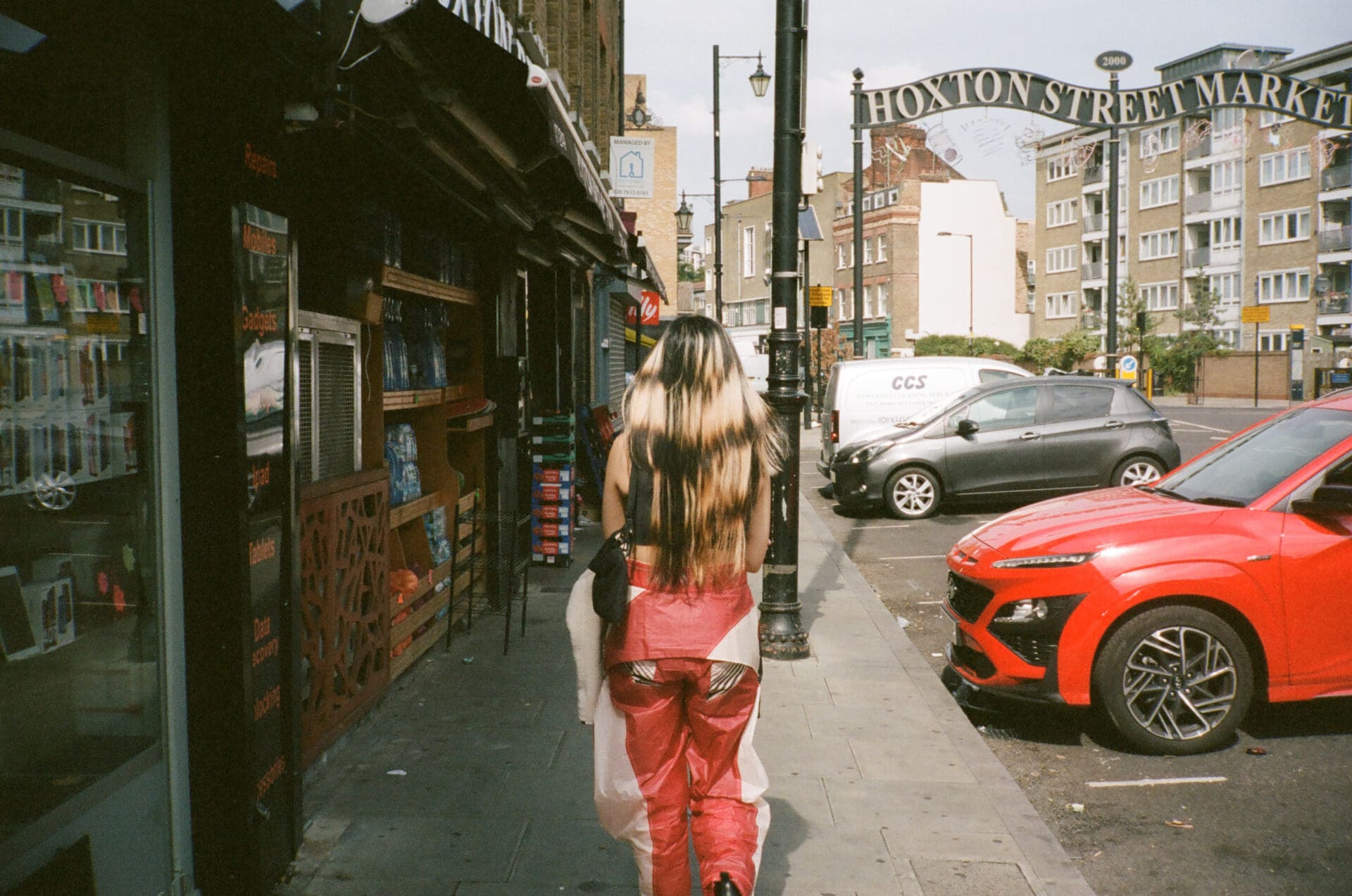 An interview with Thai pop singer Pyra | Pyra walking away from the camera towards a metal Hoxton Street Market sign curving above the road.