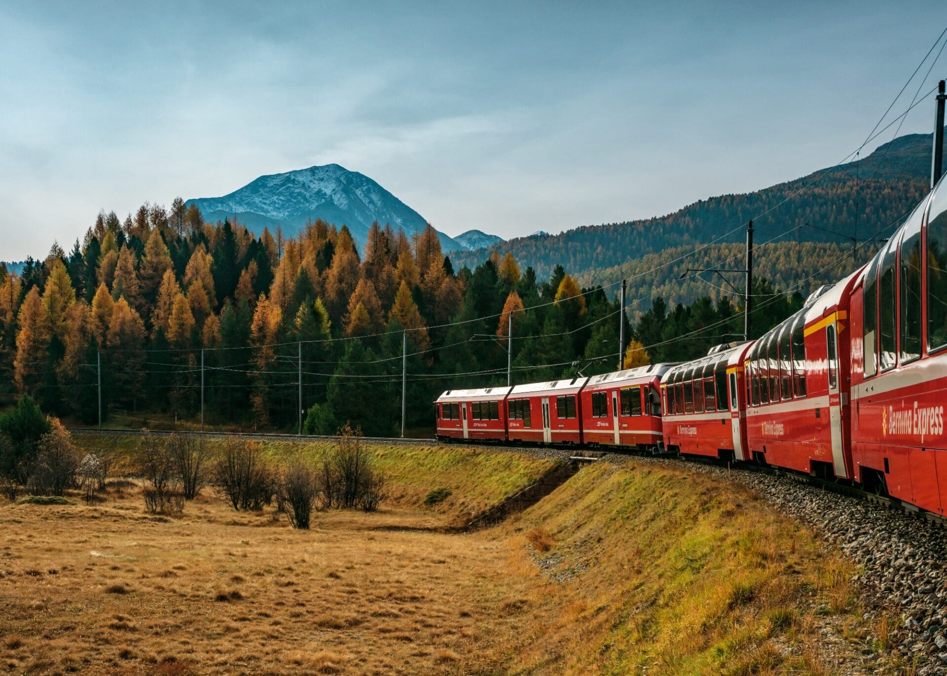 Train travel in Switzerland | A red train driving through the Swiss countryside