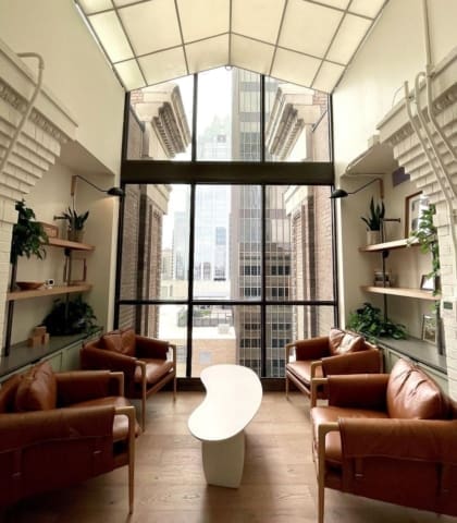 Brown leather seats against floor to ceiling windows at Common Desk, Dallas, Taxas