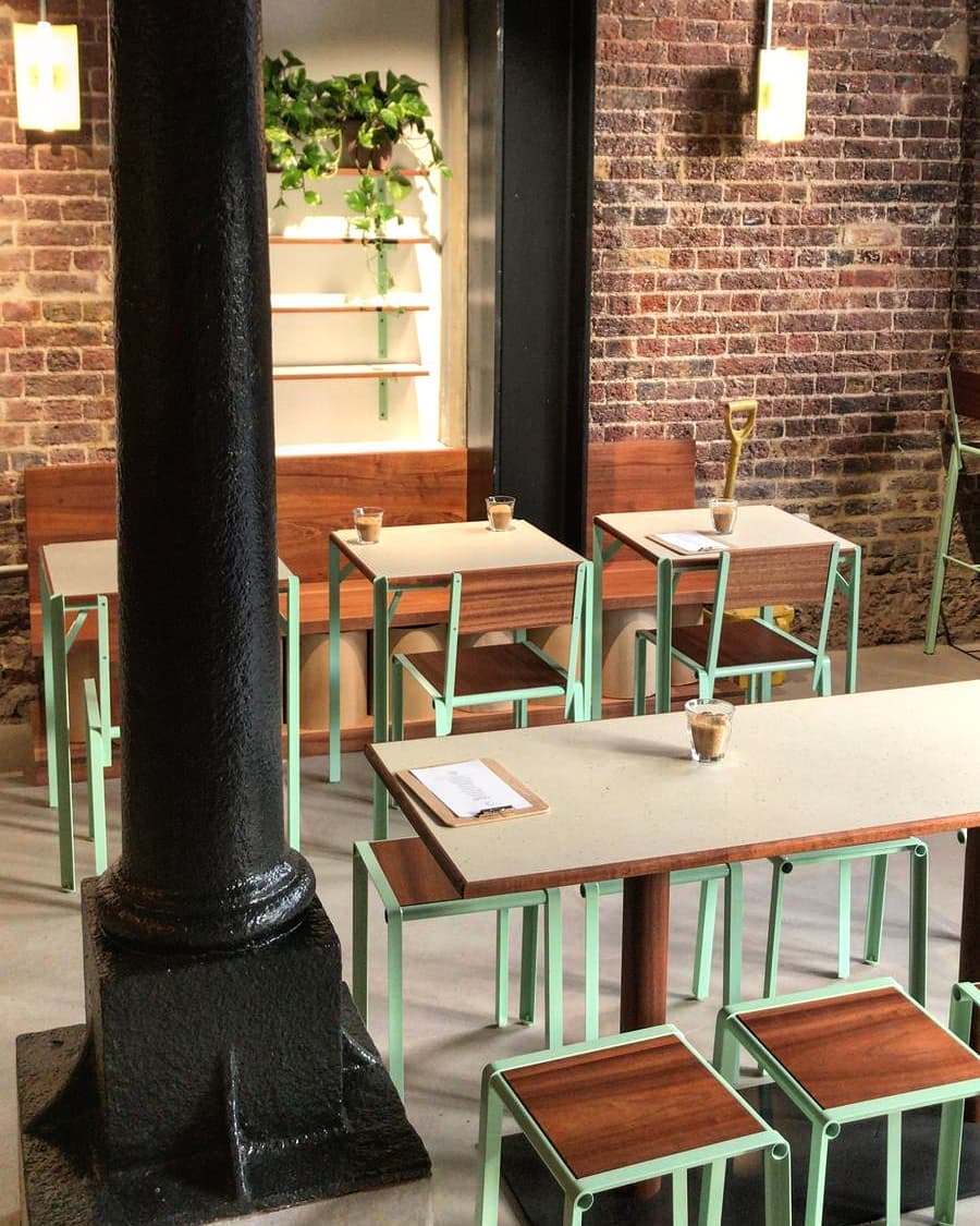 The best coffee shops in London | Red brick walls and wooden tables and stools inside Redemption Roasters