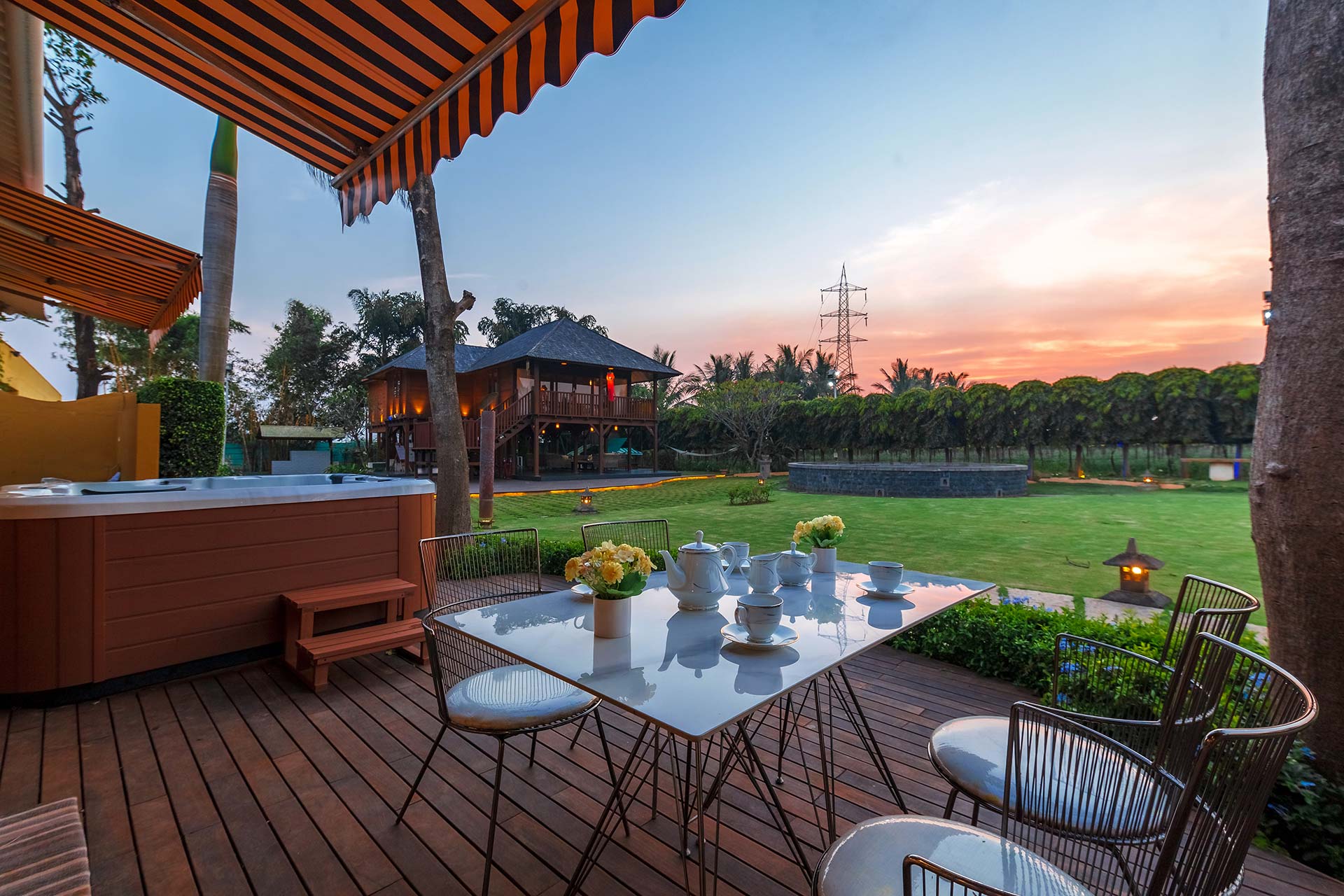 The best farm stays outside of Mumbai | A table and chairs on a wooden deck at Vedanta Farm, with a hot tub in the background under an awning