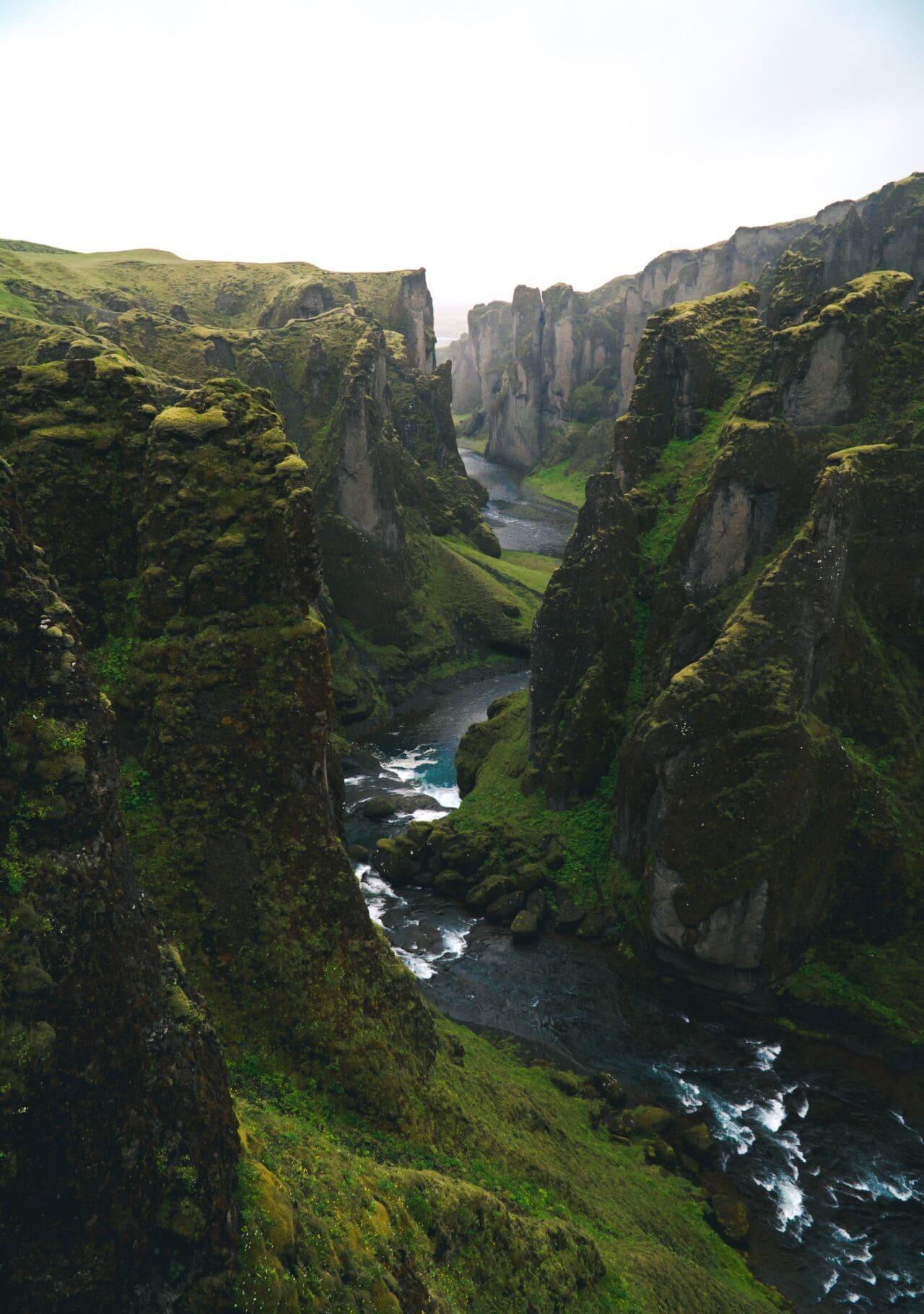 A grass-covered clifftop leading to the water, with clouds above