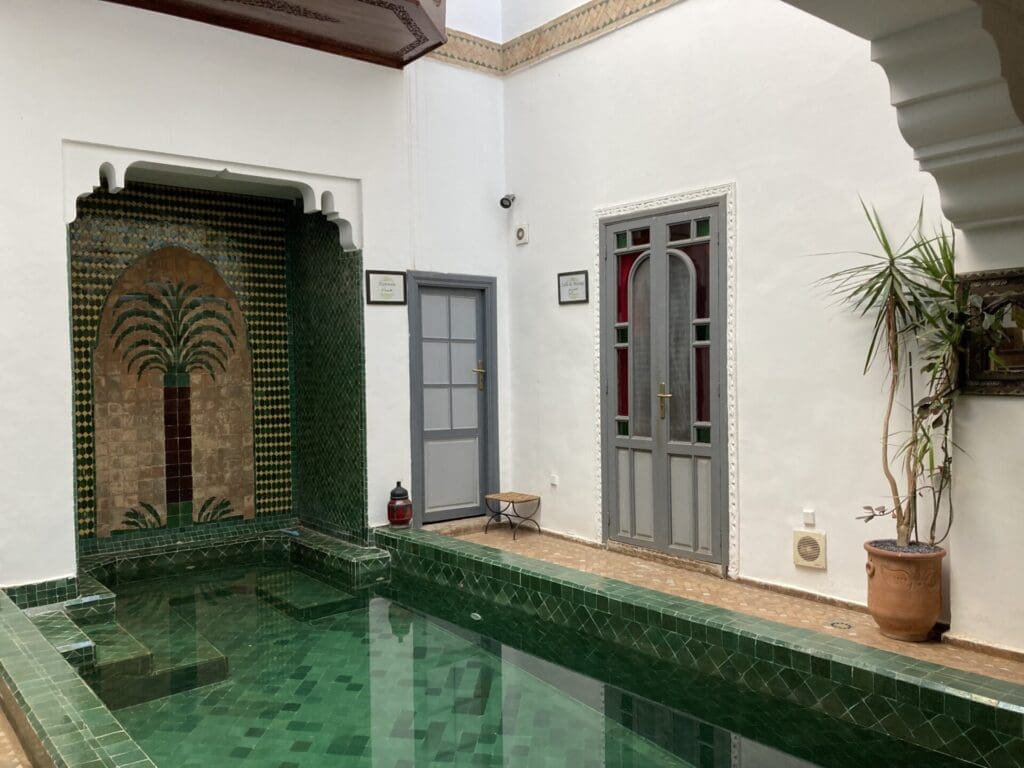 Outsite, Marrakech | a pool with green tiles and a wall mosaic