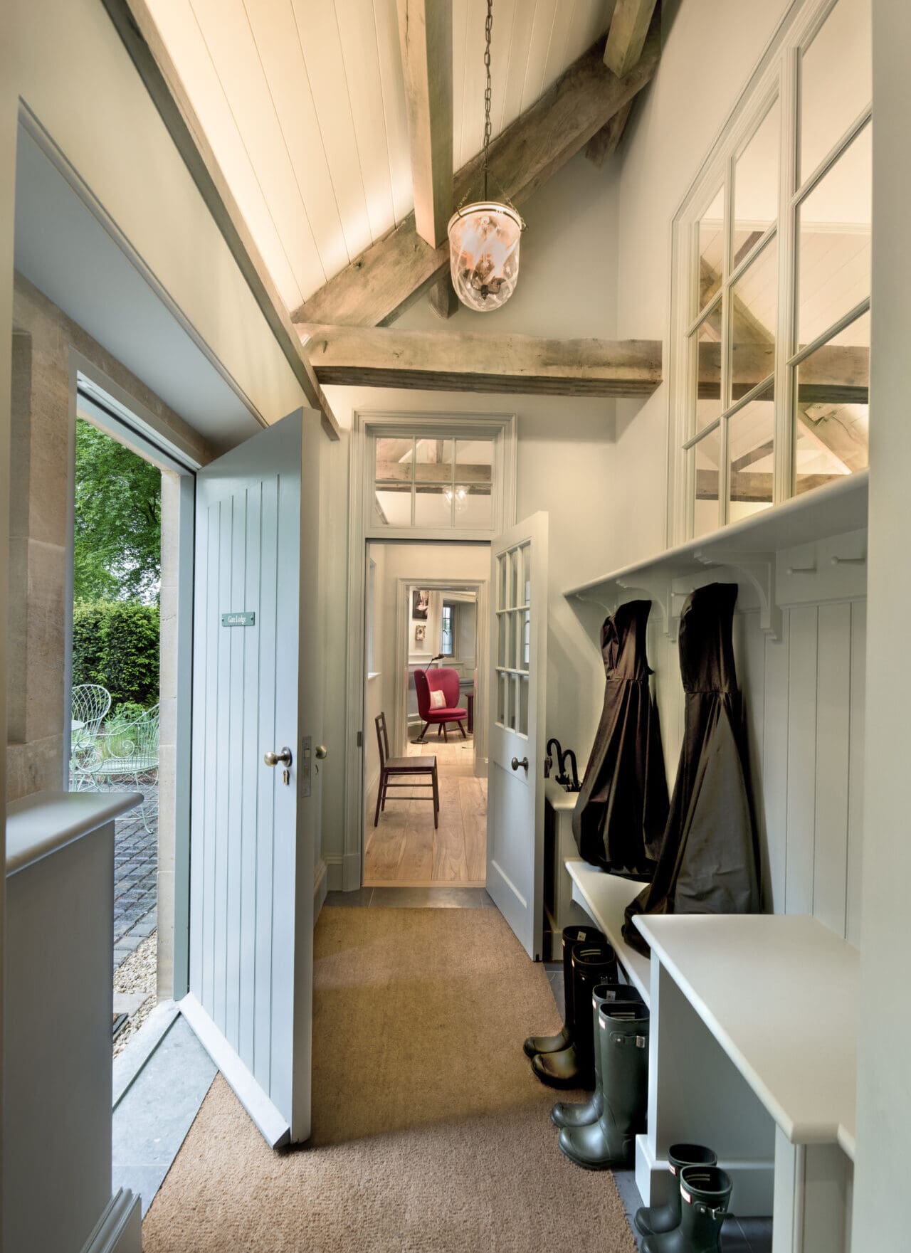 The Gate Lodge at The Newt hotel | a narrow hallway with a rustic setting, lined with boots at the door