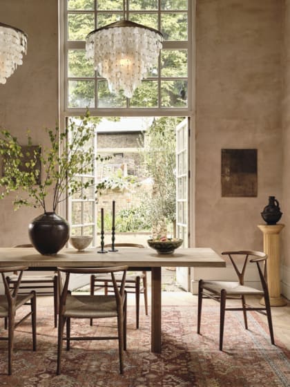 Soho Home | A chandelier above a wooden table, against a floor-to-ceiling window