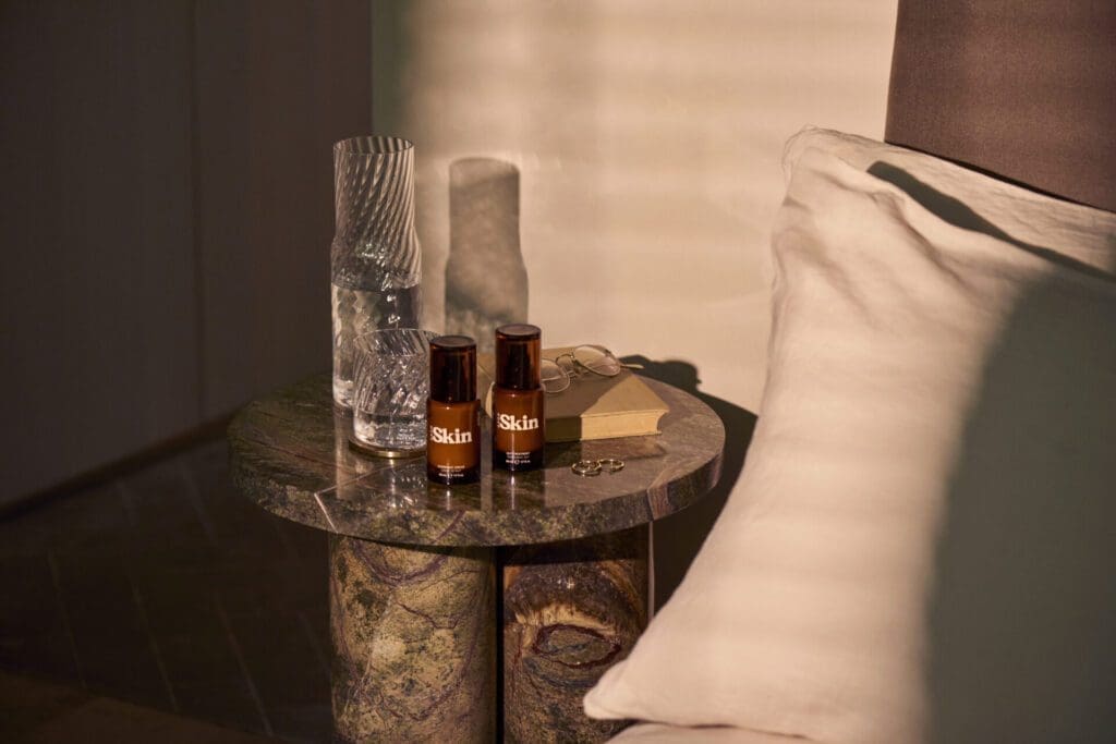 The Soho Skin line on a bedside table in a dimly lit bedroom