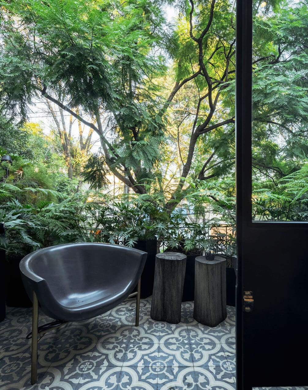 The best hotels in Roma Norte, Mexico City | A chair set on blue and white traditional Mexican tiles, surrounded by greenery