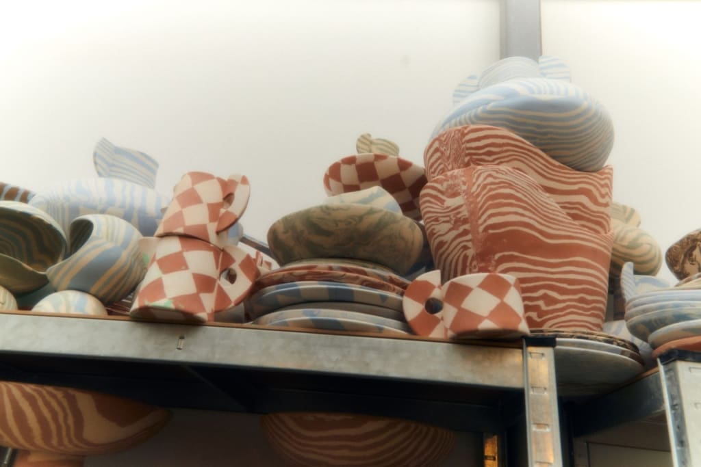 In the studio with Henry Holland | Vases, mugs, plates, bowls and planters stacked on a top shelf in the studio.