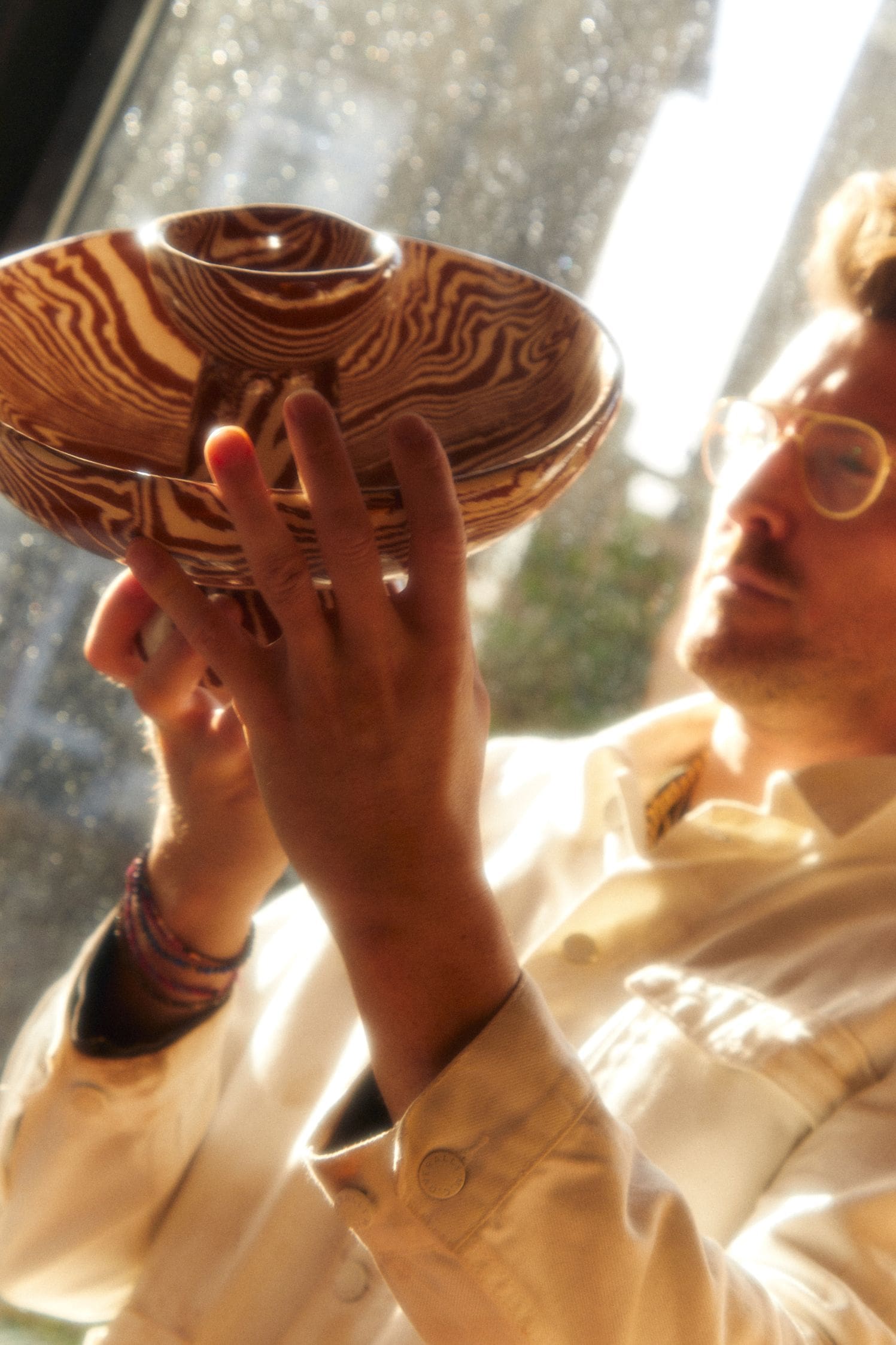 In the studio with Henry Holland | Henry Holland inspects a completed bowl in the light from the studio's glass doors.