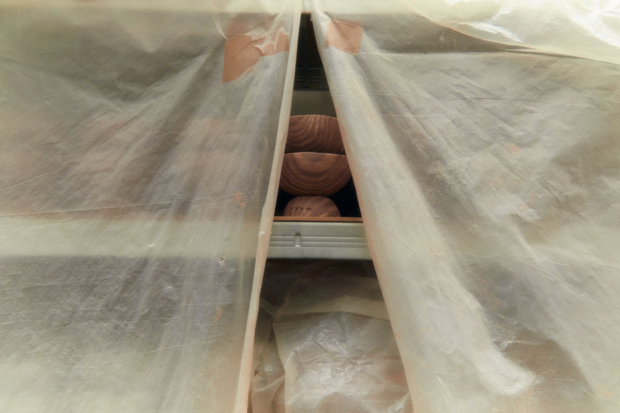 In the studio with Henry Holland | Pots on a shelf behind a dust sheet in the studio.