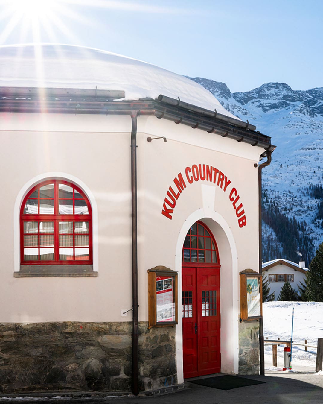 Red lettering at the The Kulm Hotel St. Moritz Club against an alpine backdrop