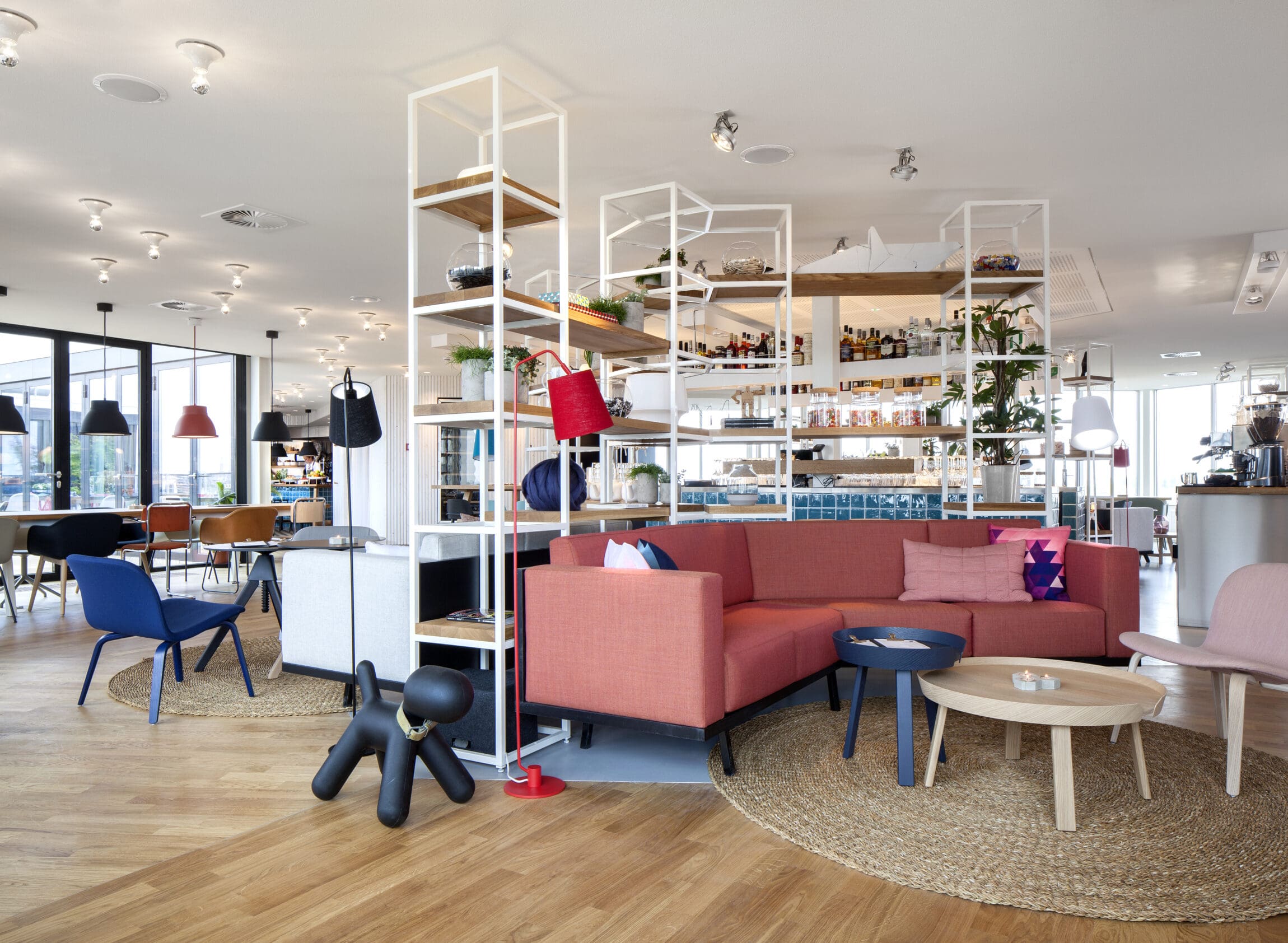 The best co-working spaces in Amsterdam for remote working | Colourful chairs and a pink couch sit around wood circular tables.
