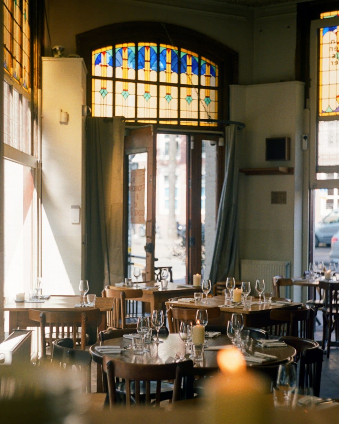 Light pours through wafting curtains at Café Binnenvisser in Amsterdam