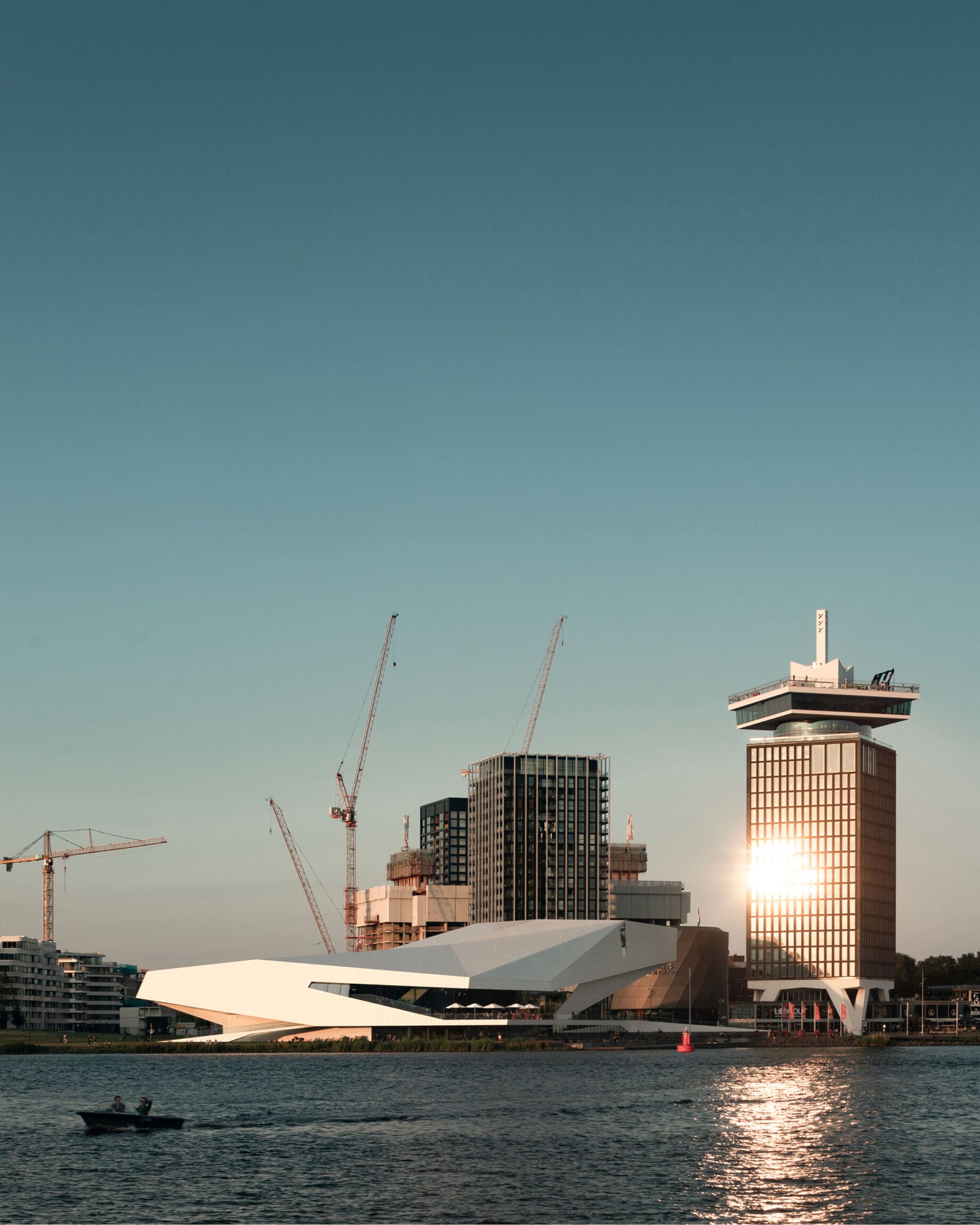 My city: Amsterdam | Boat drives along water with the city in the background