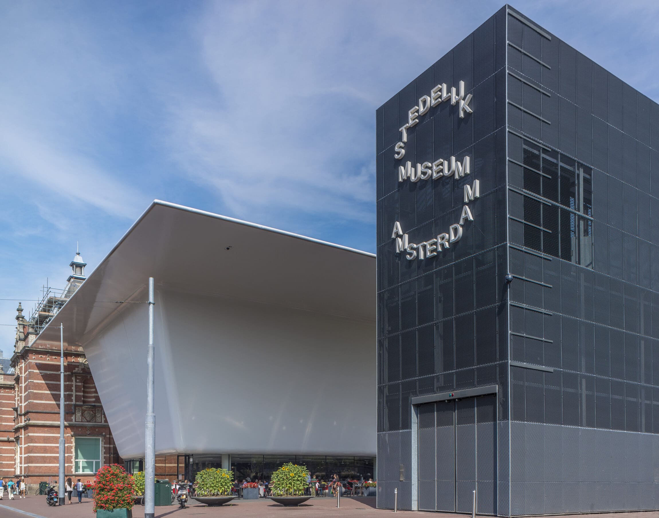 The best museums and art galleries in Amsterdam | Tall glass building with Stedelijk Museum Amsterdam written on the outside.