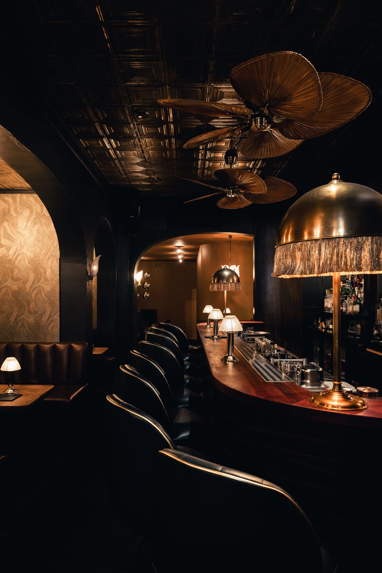 The best bars in Amsterdam | A dark wooded curved bar has lamps and fans above.