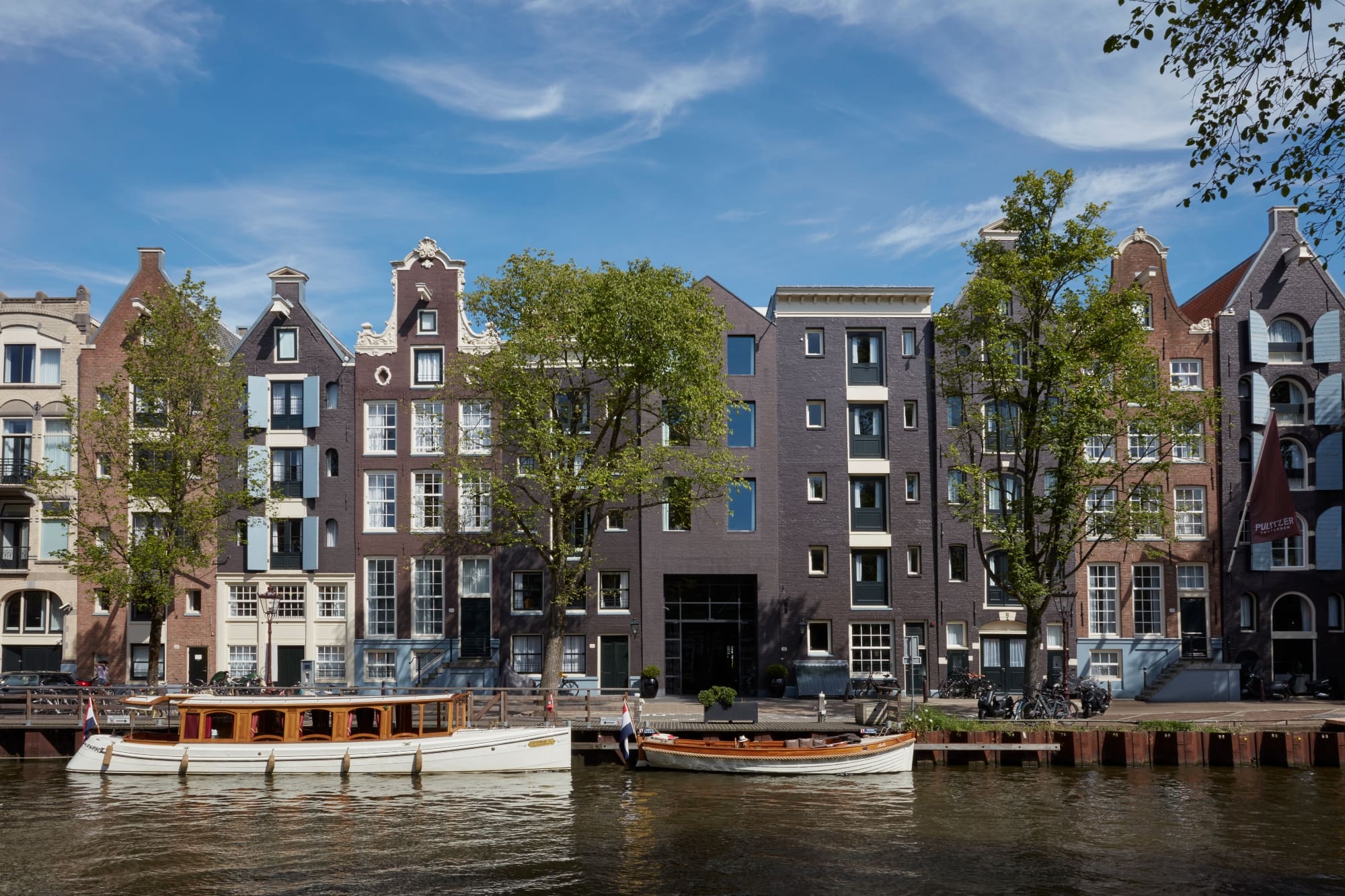 The bets hotels in Amsterdam | The Pulizer hotel sits on the edge of the canal where boats are going by.