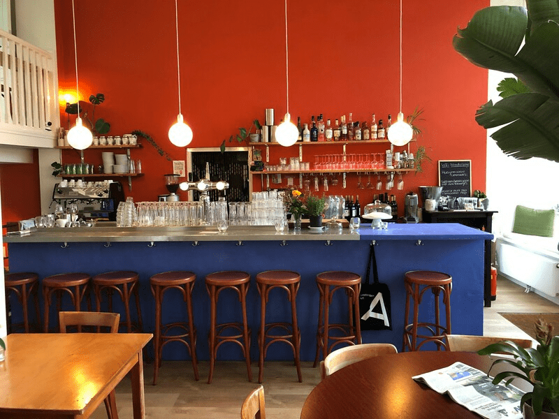 The best co-working spaces in Amsterdam for remote working | Blue bar with brown stools in front of a red painted wall.