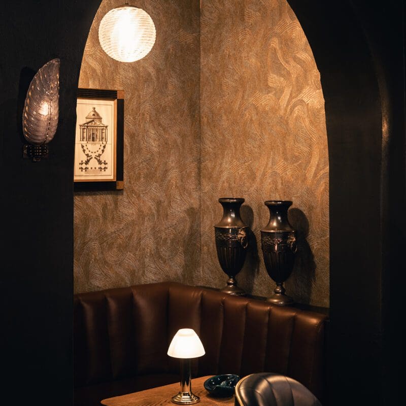 The best bars in Amsterdam | A corner booth with brown leather and a lamp on the table at Door 74
